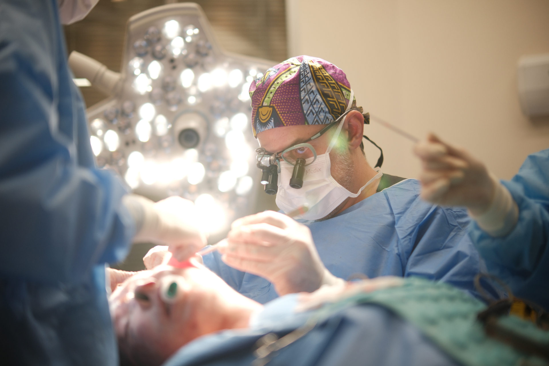 Equipe cirúrgica em procedimento facial acompanhado pelos participantes